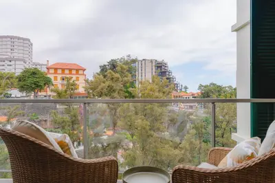 a balcony with chairs and a view of a city at FLH Funchal City View at Quinta da Nogueira Residence in Funchal