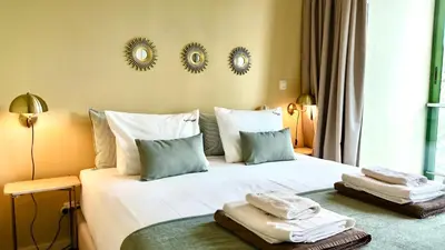 a bedroom with a white bed with towels on it at FLH Funchal City View at Quinta da Nogueira Residence in Funchal
