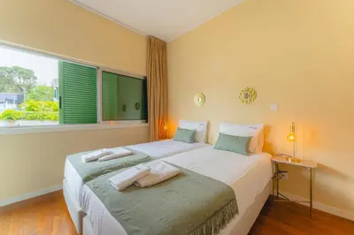 a bedroom with two beds and a large window at FLH Funchal City View at Quinta da Nogueira Residence in Funchal