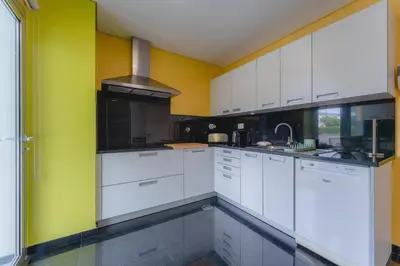 a kitchen with white cabinets and yellow walls at FLH Funchal City View at Quinta da Nogueira Residence in Funchal