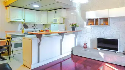 a kitchen with white cabinets and a counter with a tv at By the Sea VI - Marina in Funchal
