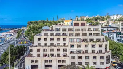 a tall white building on the side of a city at By the Sea VI - Marina in Funchal