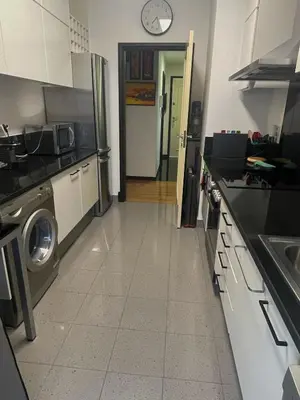 a kitchen with a refrigerator and a door with a clock at Rodamar Apartment Forum Funchal in Funchal