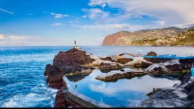 a person standing on a rock in the ocean at Rodamar Apartment Forum Funchal in Funchal