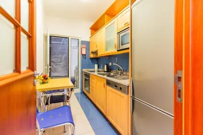 a kitchen with wooden cabinets and a table and a refrigerator at Ivory Breeze by Elysian in Funchal