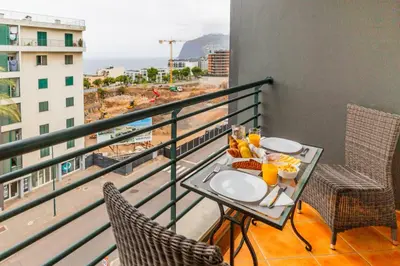 a balcony with a table with food and drinks on it at Ivory Breeze by Elysian in Funchal
