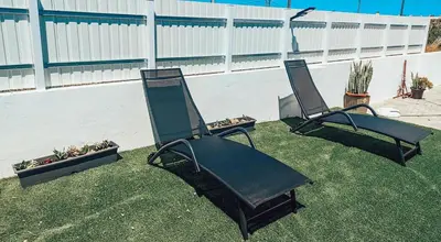 two lawn chairs sitting in the grass next to a fence at Villa Victoria, Tonel, Sagres in Sagres