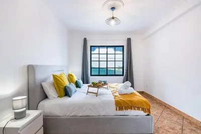 a bedroom with a bed with yellow and blue pillows at Crab House 01 by GALMI in Machico