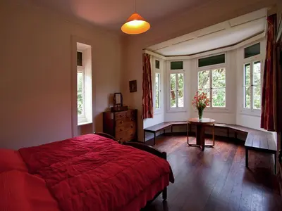 a bedroom with a bed and a table and windows at Villa Getaway in Santo António da Serra in Santo da Serra