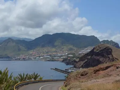 a road next to a body of water with mountains at Villa Getaway in Santo António da Serra in Santo da Serra