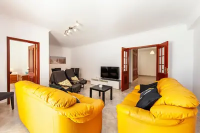 a living room with a yellow couch and a television at Topside Luz Guesthouse in Luz