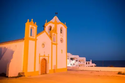 a church with a tower with a clock on it at Topside Luz Guesthouse in Luz