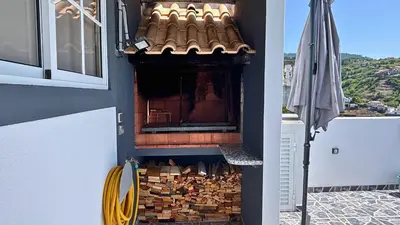 a pile of wood in a fireplace on a balcony at Golden Horizon House By Sam Houses in Ponta do Sol