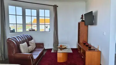 a living room with a leather chair and a television at Golden Horizon House By Sam Houses in Ponta do Sol