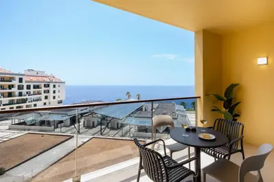 a balcony with a table and chairs and a view of the ocean at Apartamento Ajuda-Madeira by An Island Apart in Funchal
