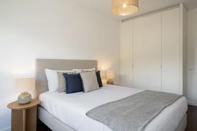 a bedroom with a large white bed with blue pillows at Apartamento Ajuda-Madeira by An Island Apart in Funchal