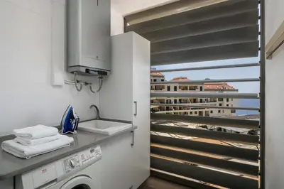 a kitchen with a washing machine and a balcony at Apartamento Ajuda-Madeira by An Island Apart in Funchal