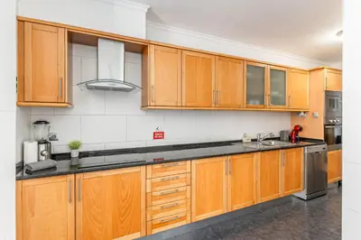 a kitchen with wooden cabinets and black counter tops at Amethyst Scape Caniço Madeira by GRM in Caniço