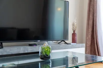 a living room with a tv and a glass table at Amethyst Scape Caniço Madeira by GRM in Caniço