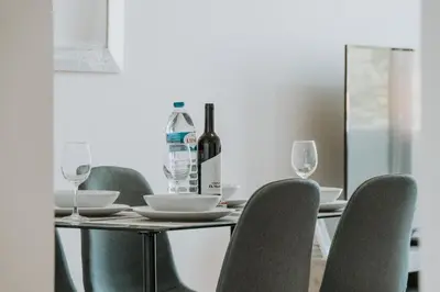 a table with chairs and a bottle of wine on it at Amethyst Scape Caniço Madeira by GRM in Caniço