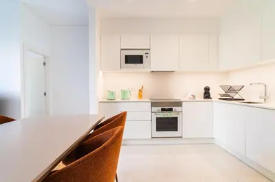 a white kitchen with a long table and chairs at GuestReady - Acqua residences in Funchal