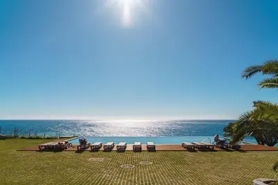 a pool with chairs and the ocean in the background at GuestReady - Acqua residences in Funchal