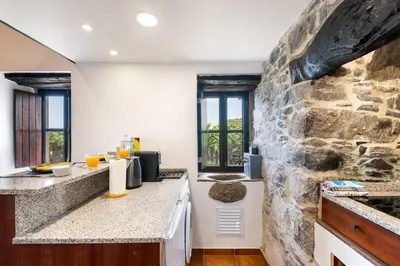 a kitchen with a stone wall at Casinha do Mar by GALMI in São Vicente