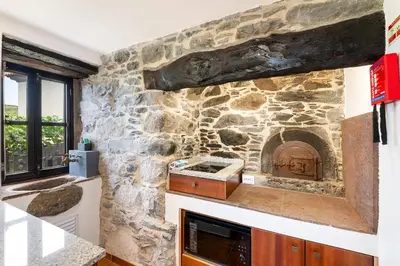 a kitchen with a stone wall with a stone oven at Casinha do Mar by GALMI in São Vicente