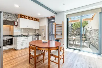 a kitchen with a wooden table and chairs in it at Port and Stone Villa in Funchal
