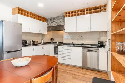 a kitchen with white cabinets and a wooden table at Port and Stone Villa in Funchal