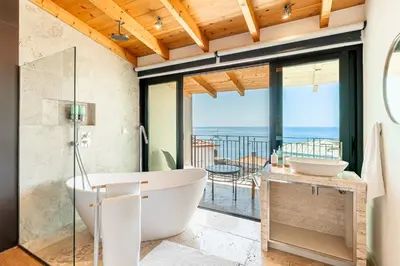a bathroom with a tub and a view of the ocean at Port and Stone Villa in Funchal