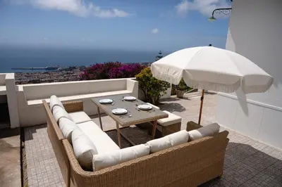 a patio with a table and chairs and an umbrella at Casa Branca do Monte in Funchal
