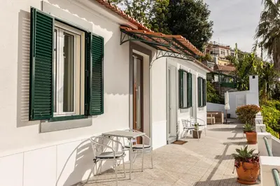 a patio with chairs and tables on a building with green shutters at Casa Branca do Monte in Funchal