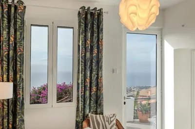 a living room with two windows with curtains at Casa Branca do Monte in Funchal