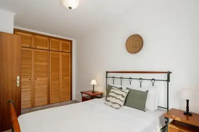 a bedroom with a white bed and a wooden closet at Apartamento da Vila by An Island Apart in Porto Santo