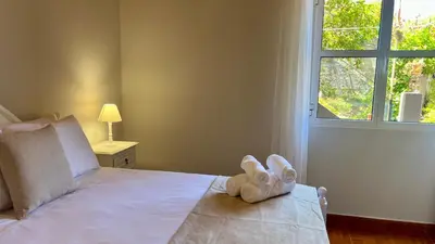 a white stuffed animal sitting on a bed with a window at Domingos Reis in São Vicente