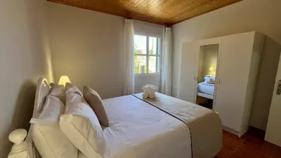 a bedroom with a large bed with white sheets at Domingos Reis in São Vicente