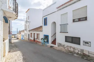 a balcony with a wooden table and white chairs at Blue House Burgau in Burgau