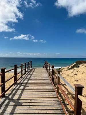 a wooden boardwalk leading to the ocean on a beach at Porto Santo Rentals in Porto Santo