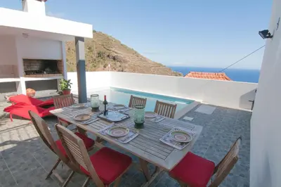 a wooden table and chairs on a patio with the ocean at Casa Nici in Calheta
