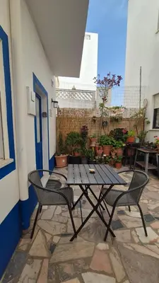 a table and chairs on a patio with plants at Casa da Praia Burgau in Burgau