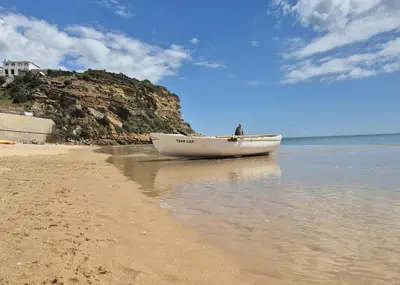 a boat sitting on the sand on the beach at Casa da Praia Burgau in Burgau