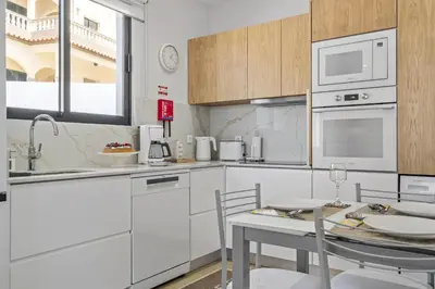 a kitchen with white cabinets and a table with chairs at Orinoco Sunset House I - Private Jacuzzi in Calheta