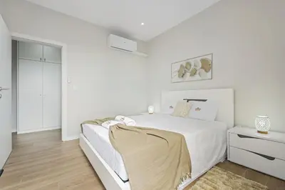 a white bedroom with a white bed and a wooden floor at Orinoco Sunset House I - Private Jacuzzi in Calheta