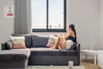 a woman sitting on a couch in a living room at Orinoco Sunset House I - Private Jacuzzi in Calheta