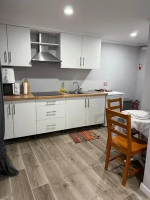 a kitchen with white cabinets and a sink and a chair at Casa Camacho - Santa Cruz in Santa Cruz