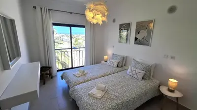 a bedroom with two beds and a large window at Apartamento Magnólia in Lagos