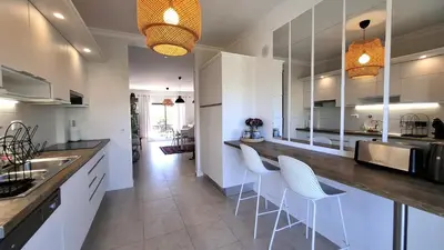a kitchen with white cabinets and a counter with white chairs at Apartamento Magnólia in Lagos