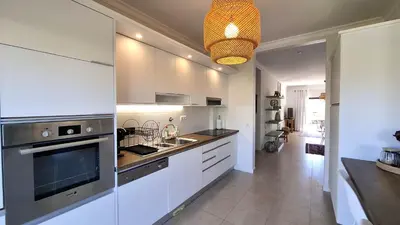 a kitchen with white cabinets and a sink and a microwave at Apartamento Magnólia in Lagos