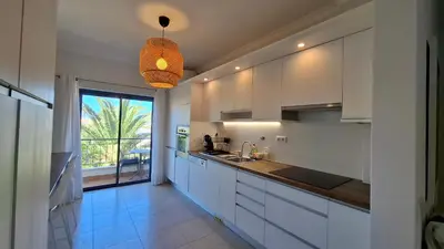 a kitchen with white cabinets and a large window at Apartamento Magnólia in Lagos